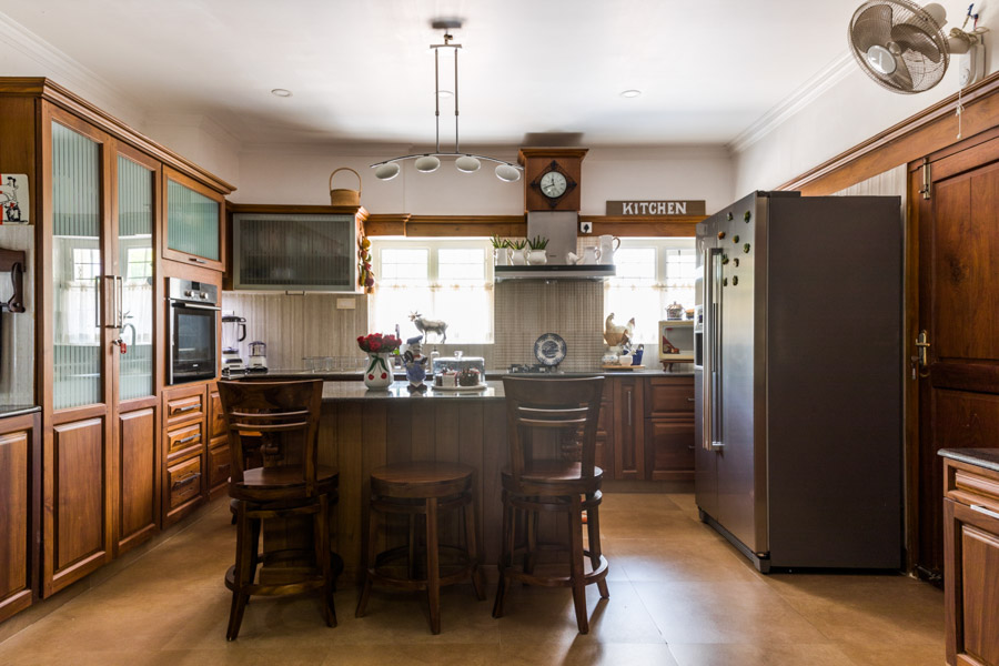 Open interior kitchen design with an island in the middle, dark wooden furniture and dark brown refrigerator - Beautiful Homes